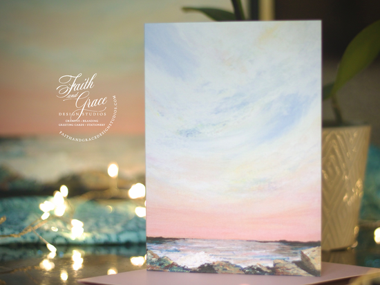 Painting of Dusk on the Rocks by Kristina Petrilli in greeting card form with trinkle lights blurry in the background.